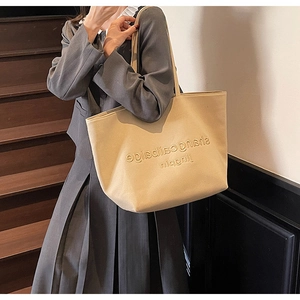 Close-up of beige canvas tote bag with embossed lettering on vintage wooden stairs