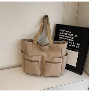 Detail view of khaki canvas tote bag featuring functional front zipper pockets and durable straps