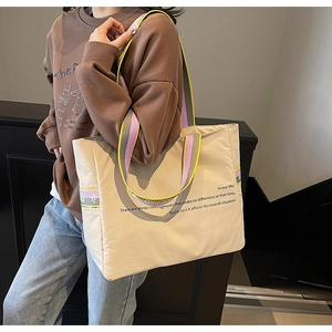 Détail du sac cabas en toile avec bandoulières rayées tricolores et texte imprimé