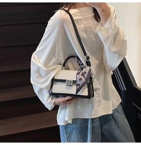 Détail du sac à bandoulière bicolore avec texture tissée crème et finitions en cuir