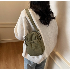 Detail view of the olive green nylon crossbody bag showing the adjustable shoulder strap