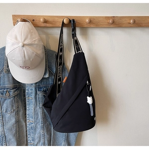 Detail of black crossbody sling bag with adjustable SJCHAO strap and orange label