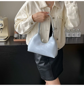 Close-up of light blue patent leather hobo bag with sleek minimalist shoulder strap detail