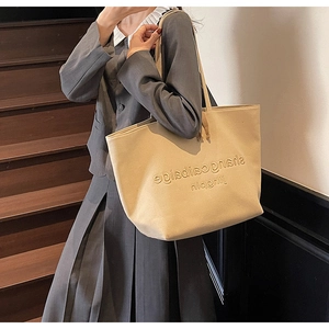 Spacious beige canvas tote bag shown on a model's shoulder for office and casual style