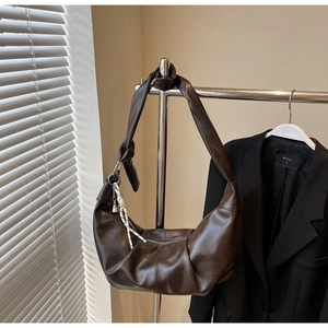 Detail of a dark brown slouchy crescent bag with knotted strap and soft leather texture