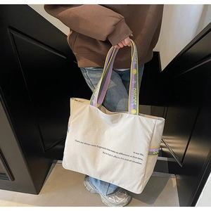Détail du grand sac cabas en toile beige avec sangles contrastées violet et jaune