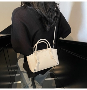 Modella indossa borsa tote crema in pelle con dettagli a nodo e tracolla sottile