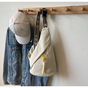 Detail of off-white crossbody bag featuring a jacquard strap and yellow cord ornament