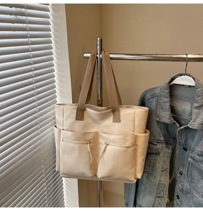 Detail showing cream canvas tote bag with brown handles and utility front pockets