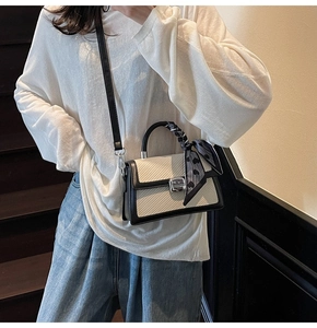 Détail du sac bandoulière contrasté avec boucle argentée et foulard en soie à cœurs