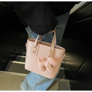 Detail der rosa PU-Leder-Einkaufstasche mit Sternprägung und süßem Plüsch-Hundeanhänger