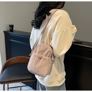Close-up of pink nylon crossbody bag showing drawstring pocket and wrinkled texture