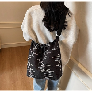 Close-up of black quilted canvas tote featuring wavy white and purple embroidery detail