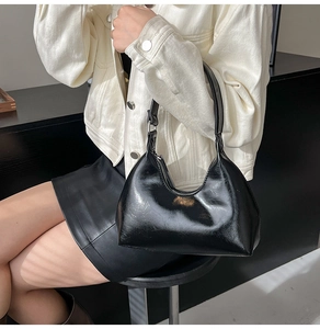Chic glossy black crescent hobo bag made of shiny PU leather shown on a model