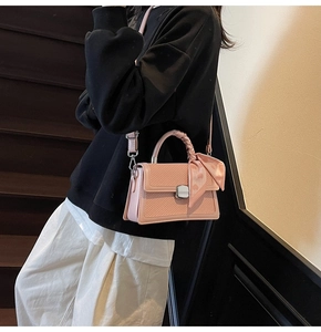 Détail du sac bandoulière rose avec rabat tissé et poignée ornée d'un foulard en soie