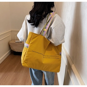 Détail du sac cabas en toile jaune moutarde avec bandoulière violette logotypée