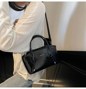 Dettaglio della borsa tote in pelle nera lucida con manico a nodo e logo bianco