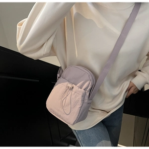 Detail of lilac nylon crossbody phone bag featuring adjustable strap and drawstring pocket
