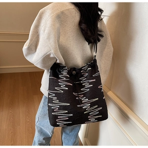 Detail of canvas bucket bag featuring colorful zigzag embroidery and logo texture