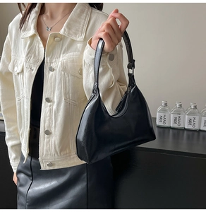 Close-up of a minimalist black crescent shoulder bag with metallic zipper and sleek finish