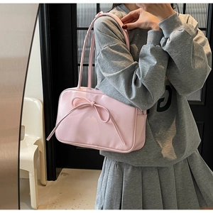 Detailed close-up of a pink shoulder bag featuring a large decorative bow and leather texture