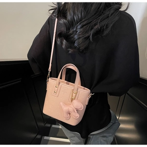 Nahaufnahme der rosa Beuteltasche mit Sternprägung und Welpen-Anhänger-Detail