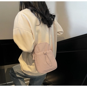 Close-up of lightweight pink nylon crossbody bag with drawstring pocket and strap