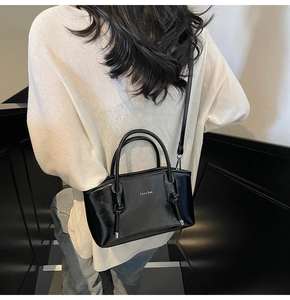 Borsa tote in pelle nera indossata da modella con tracolla e dettaglio del logo