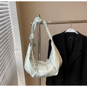 Detail of soft cream hobo bag with knotted wide strap and textured charm