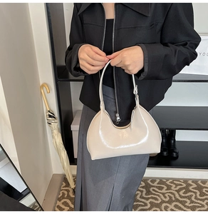 Detail of a creamy white glossy patent leather baguette bag with metal zipper and handle