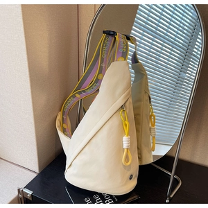 Detail of off-white chest bag with colorful adjustable strap and yellow zipper cord