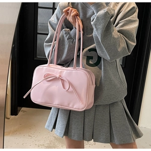 Close-up of the delicate pink bow knot detail on a glossy leather crossbody tote bag