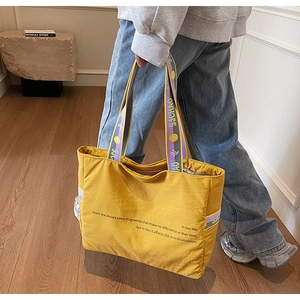 Détail du sac cabas en nylon jaune avec anses violettes et imprimé artistique