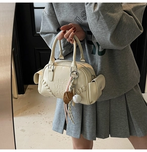 Detail of cream shoulder bag featuring baseball stitching and Cult Vat embossed logo