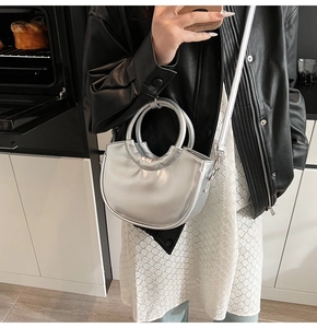 Metallic silver half-moon bag featuring round top handles and a glossy mirror finish