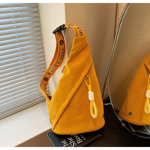 Detail view of a bright yellow triangular chest bag with floral print shoulder strap