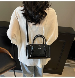 Dettaglio borsa tote in pelle nera lucida con logo argento e tracolla regolabile