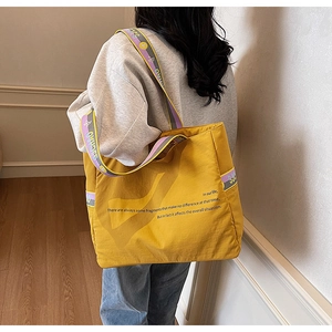 Détail du sac cabas jaune avec bandoulière violette contrastée et motif texte imprimé
