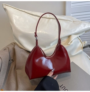 Detail of red glossy patent leather hobo bag with a silver zipper and half-moon design