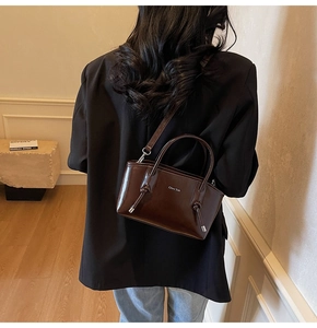 Dettaglio della borsa tote in pelle lucida marrone scuro con eleganti manici annodati