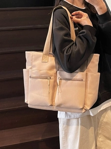 Minimalist beige canvas tote bag with multiple pockets worn by model on stairs