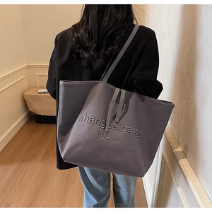 Deep grey large capacity canvas tote bag with embossed letters shown on model back