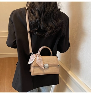 Détail du sac beige avec texture tissée, fermoir métallique et poignée en foulard rose