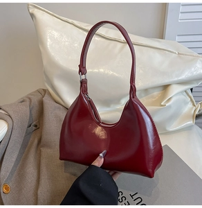 Detailed macro view of the dark red hobo bag showing glossy faux leather texture