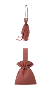 Macro detail of brick red nylon drawstring pouch with drawstring closure and handle