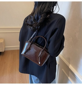 Dettaglio della borsa tote marrone vintage con texture lucida e ciondolo a nodo
