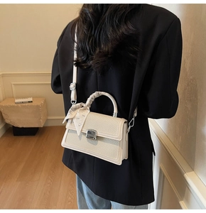 Détail du sac tissé avec fermoir argenté et foulard en soie sur la poignée haute