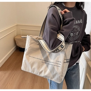 Détail d'un cabas en toile avec bandoulière jacquard et texte imprimé minimaliste