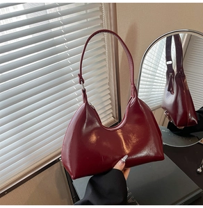 Macro shot of dark red polished leather bag with silver zipper in front of a mirror