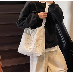 Detailed shot of white canvas crossbody bucket bag with colorful embroidery and strap
